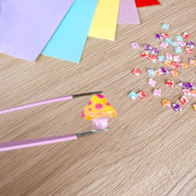 Load image into Gallery viewer, A close-up of a yellow and red spotted toadstool held by tweezers over a craft table
