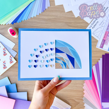 Load image into Gallery viewer, A half-rainbow iris folding card with punched paper hearts
