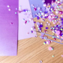 Load image into Gallery viewer, Close-up of a purple gem on a wooden surface with tweezers.
