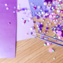 Load image into Gallery viewer, Close-up of a purple gem on a wooden surface with tweezers.

