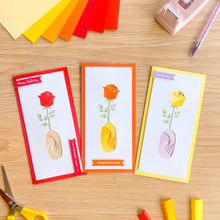Load image into Gallery viewer, Three iris fold greeting cards with rose designs on a wooden surface with craft supplies.
