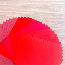 Load image into Gallery viewer, Stack of red paper on a wooden surface

