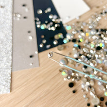 Load image into Gallery viewer, Close-up of a wooden surface with tweezers holding a single gem
