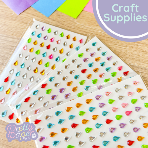 Colorful rhinestone teardrop stickers on a wooden surface with 'Pretty Paper' branding.