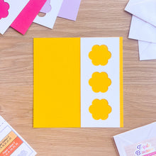 Load image into Gallery viewer, Yellow card with white flower cut-out with pink and purple cards in the background
