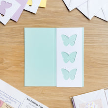 Load image into Gallery viewer, Butterfly cut-outs on a scored card with other cards in the background on a wooden surface
