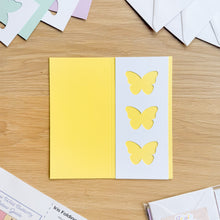 Load image into Gallery viewer, Yellow butterfly cutouts on a card with additional cards and materials on a wooden surface
