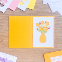 Load image into Gallery viewer, Buttercup coloured card blank with tulip aperture on a wooden surface
