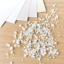 Load image into Gallery viewer, White pearls and rhinestones on a wooden surface
