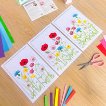 Load image into Gallery viewer, Triptych of iris folding flower pictures on a wooden surface with paper craft supplies.
